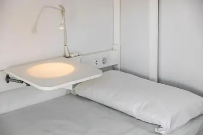a small room with a bed and a lamp at Urbany Hostel BCN GO! in Barcelona