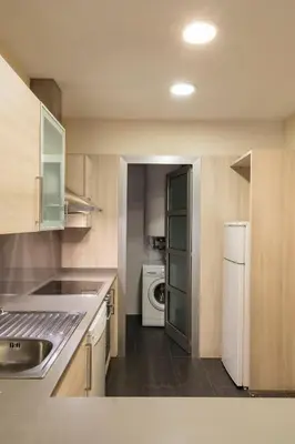 a kitchen with white appliances and wooden cabinets at Barcelona Apartment Villarroel in Barcelona