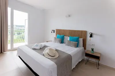 a white bedroom with a large bed with a hat on it at Bamblue Boutique Apartments in Pineda de Mar