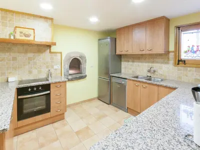 a kitchen with wooden cabinets and stainless steel appliances at 17th century farmhouse in Bages, near Montserrat in Castellfullit del Boix