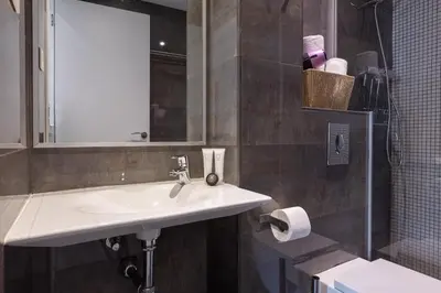 a bathroom with a sink and a mirror and a toilet at Enjoybcn Patio de Gala in Barcelona