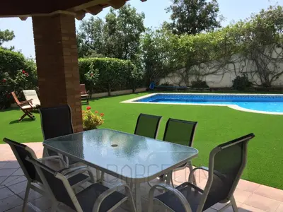 a table and chairs next to a swimming pool at BarcelonaVacances-Villa Lucia in San Pol de Mar