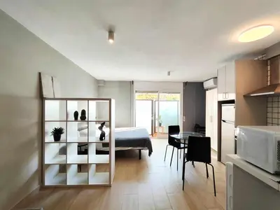 a room with a bed and a kitchen with a table at Mazi Apartments Suite in Mataró