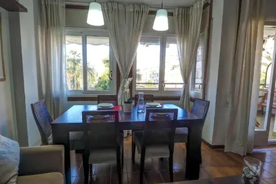 a dining room with a table and chairs and windows at Clarimar Apartment by Hello Homes Sitges in Sitges