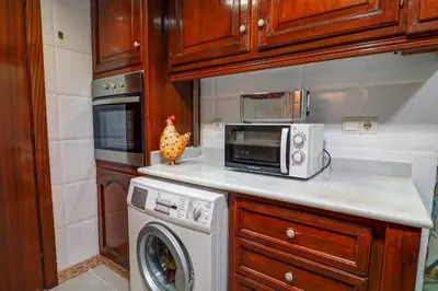 a kitchen with a washing machine and a microwave at Clarimar Apartment by Hello Homes Sitges in Sitges