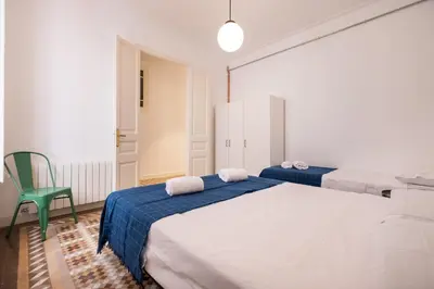 a bedroom with two beds and a green chair at b32-Sunny and Modernist apartment for groups in center in Barcelona