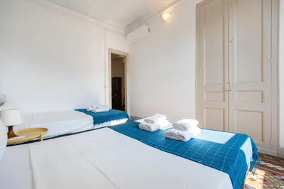 two beds in a white room with blue sheets and towels at b21-Apartamento Modernista para Grupos in Barcelona