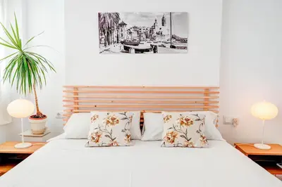 a bedroom with a white bed with two lamps at Secret Garden Apartment by Hello Homes Sitges in Sitges