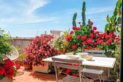 a white table with red flowers on a balcony at Secret Garden Apartment by Hello Homes Sitges in Sitges