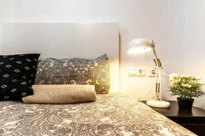 a bedroom with a bed with a lamp and pillows at Magnifico apartamento camp nou in Barcelona