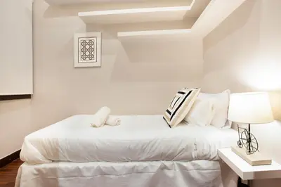 a white bedroom with a bed and a lamp at Stay U-nique Apartments Calvet in Barcelona