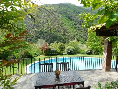 a patio with a table and chairs next to a pool at Can Barrina in Montseny