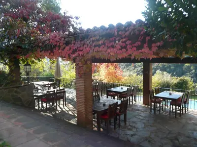 a patio with tables and chairs under a pergola with pink flowers at Can Barrina in Montseny