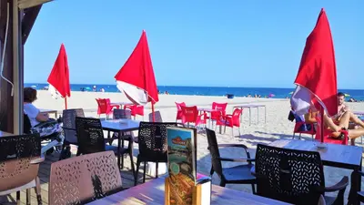 a beach with tables and chairs and red flags at MARILU SEAVIEW & BEACH - apartment in Masnou