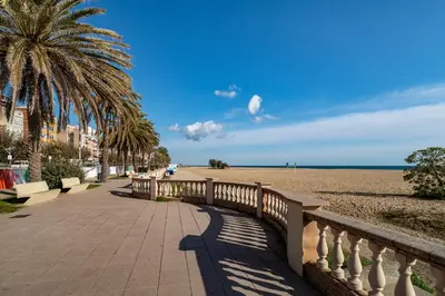 a bridge over a sandy beach with a palm tree at MARILU SEAVIEW & BEACH - apartment in Masnou