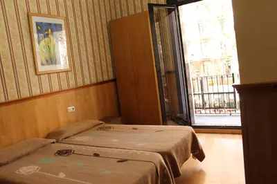 a hotel room with two beds and a window at Pensión Villanueva in Barcelona
