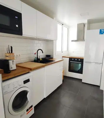 a kitchen with white cabinets and a washing machine at Precioso apartamento en la playa Barcelona in Cabrera de Mar