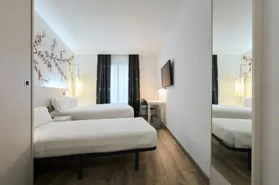 a hotel room with two beds and a mirror at Catalonia La Boquería in Barcelona