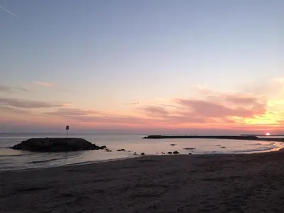 a sunset on a beach with a rock in the water at Apartamento Primera Linea de Mar, Cunit in Cunit