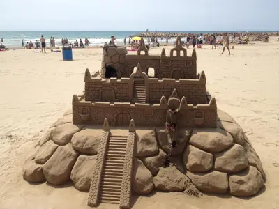 a sand castle on the beach with people in the background at Apartamento Primera Linea de Mar, Cunit in Cunit