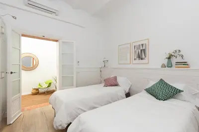 two beds in a white room with a window at Casa Cosi - Eixample 1 in Barcelona