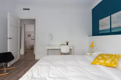 a bedroom with a white bed and a desk at Casa Cosi - Eixample 2 in Barcelona