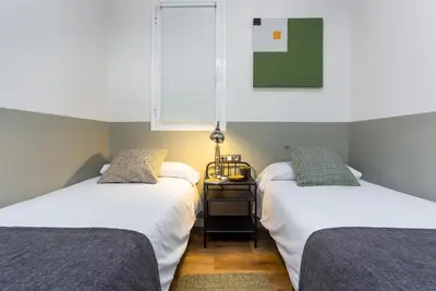 two beds in a room with a table and a window at Ola Living Music in Barcelona
