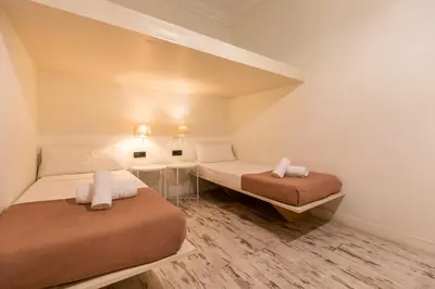 a small room with two beds and a table at eg21- MODERNIST AND ELEGANT APARTMENT IN BCN CITY CENTER in Barcelona