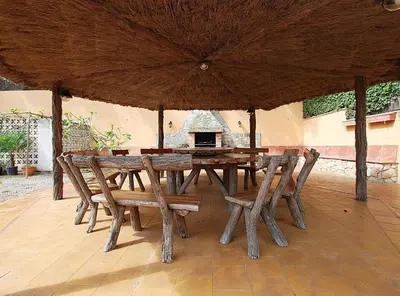 a wooden table and chairs under a large umbrella at Villa Magnolia in Mataró