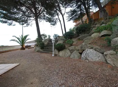 a path with rocks and trees and a building at Villa Magnolia in Mataró