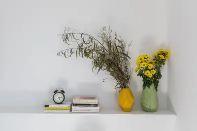 two vases and a clock on a shelf with flowers at Casa Cosi - Eixample 3 in Barcelona