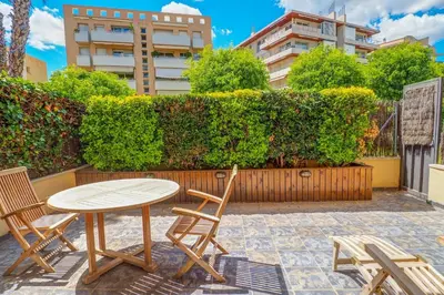 a patio with a table and chairs and a hedge at Megan Apartment by Hello Homes Sitges in Sitges
