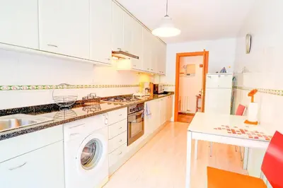 a kitchen with white cabinets and a washer and dryer at Megan Apartment by Hello Homes Sitges in Sitges