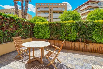a table and chairs on a patio with a hedge at Megan Apartment by Hello Homes Sitges in Sitges