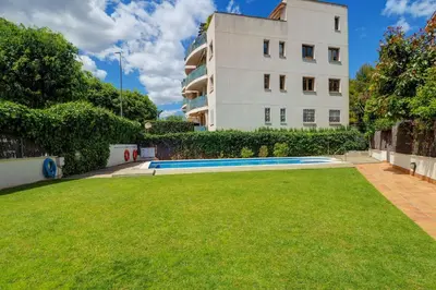 a building with a grassy yard in front of a building at Megan Apartment by Hello Homes Sitges in Sitges