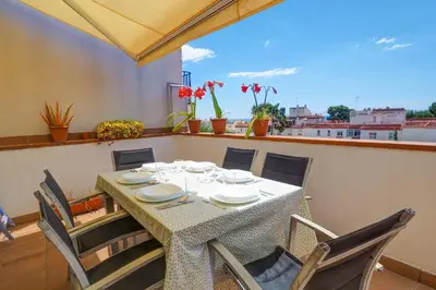 a dining room table with chairs and a large window at Portman Duplex by Hello Homes Sitges in Sitges