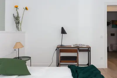 a bedroom with a bed and a desk and a vase with flowers at Casa Cosi - Eixample 4 in Barcelona