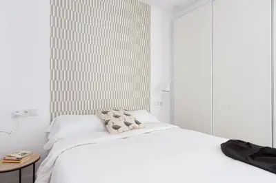 a white bedroom with a bed and a table at Casa Cosi - Eixample 4 in Barcelona