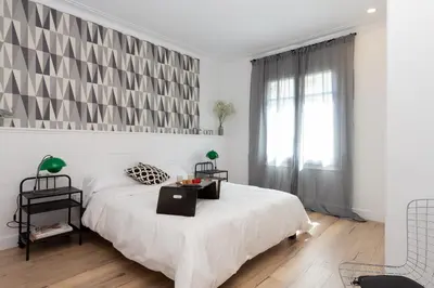 a white bedroom with a large bed and a window at Casa Cosi - Eixample 4 in Barcelona