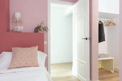 a bedroom with a white bed and a pink wall at Casa Cosi - Eixample 5 in Barcelona
