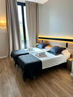 a bedroom with two beds and a large window at Hostalin Barcelona Gran Via in Barcelona