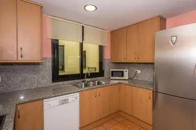 a kitchen with wooden cabinets and a stainless steel refrigerator at HomeHolidaysRentals Escapade in Pineda de Mar