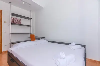 a bedroom with a bed with white sheets and towels at HomeHolidaysRentals Escapade in Pineda de Mar
