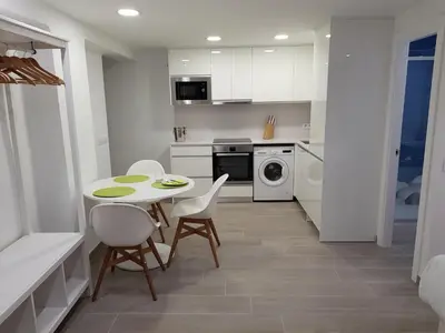 a white kitchen with a table and chairs in it at Krm Suite Apartament in Calella