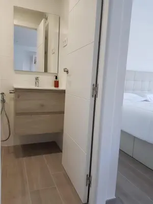 a white bathroom with a sink and a mirror at Krm Suite Apartament in Calella