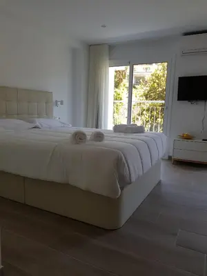 a white bedroom with a large bed with a window at Krm Suite Apartament in Calella