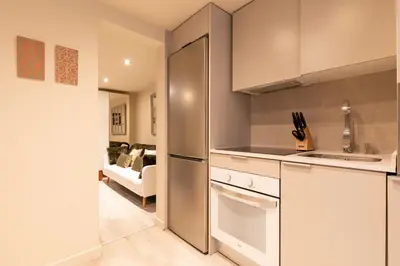 a kitchen with a stainless steel refrigerator and a living room at Chic Apartments Barcelona in Barcelona