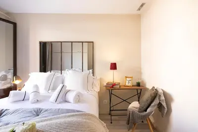 a bedroom with a bed with white pillows and a chair at Chic Apartments Barcelona in Barcelona