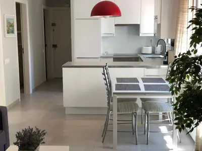 a kitchen with white cabinets and a table and chairs at Discover Sitges Center&Beach, a un minuto del mar in Sitges