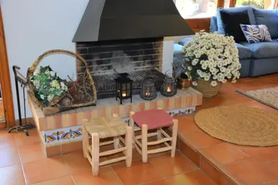 a living room with a fireplace with two chairs and a table at Villa Sitges Colibri at 10 min Walk Beaches - Center City Amaizing Garden Pool XXL Private Tenis Piste in Vilanova i la Geltrú